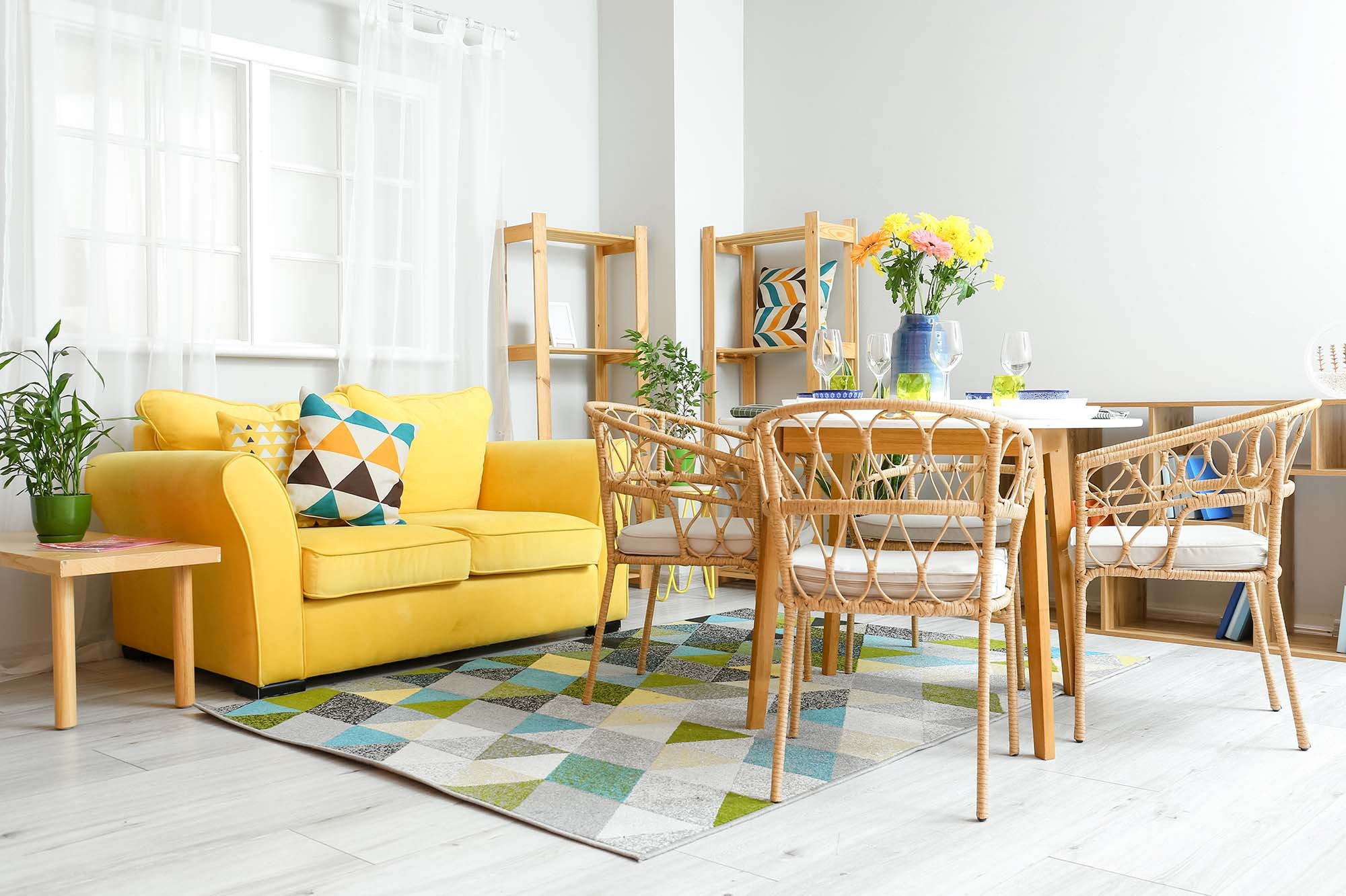 yellow couch and wood table and chairs on a patterned color rug in a bright living room with white hardwood floor from Stoller Floors in Orrville, OH